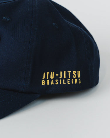 Side view of navy blue Gracie Barra Lutador Cap with gold embroidered text reading “Jiu-Jitsu Brasileiro.”
