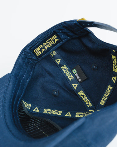 Inside view of navy blue Gracie Barra Lutador Cap with gold branded taping reading “Gracie Barra” and woven Brazil flag tag.