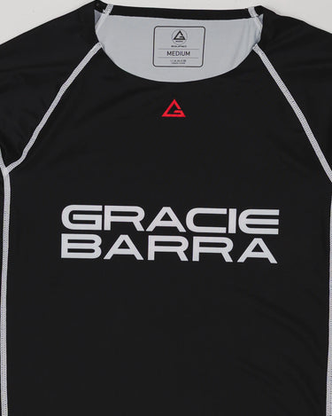 Close-up of the black Lutador long-sleeve ranked rashguard showing the GRACIE BARRA chest print, red Legacy G triangle emblem at the collar, and white contrast stitching.