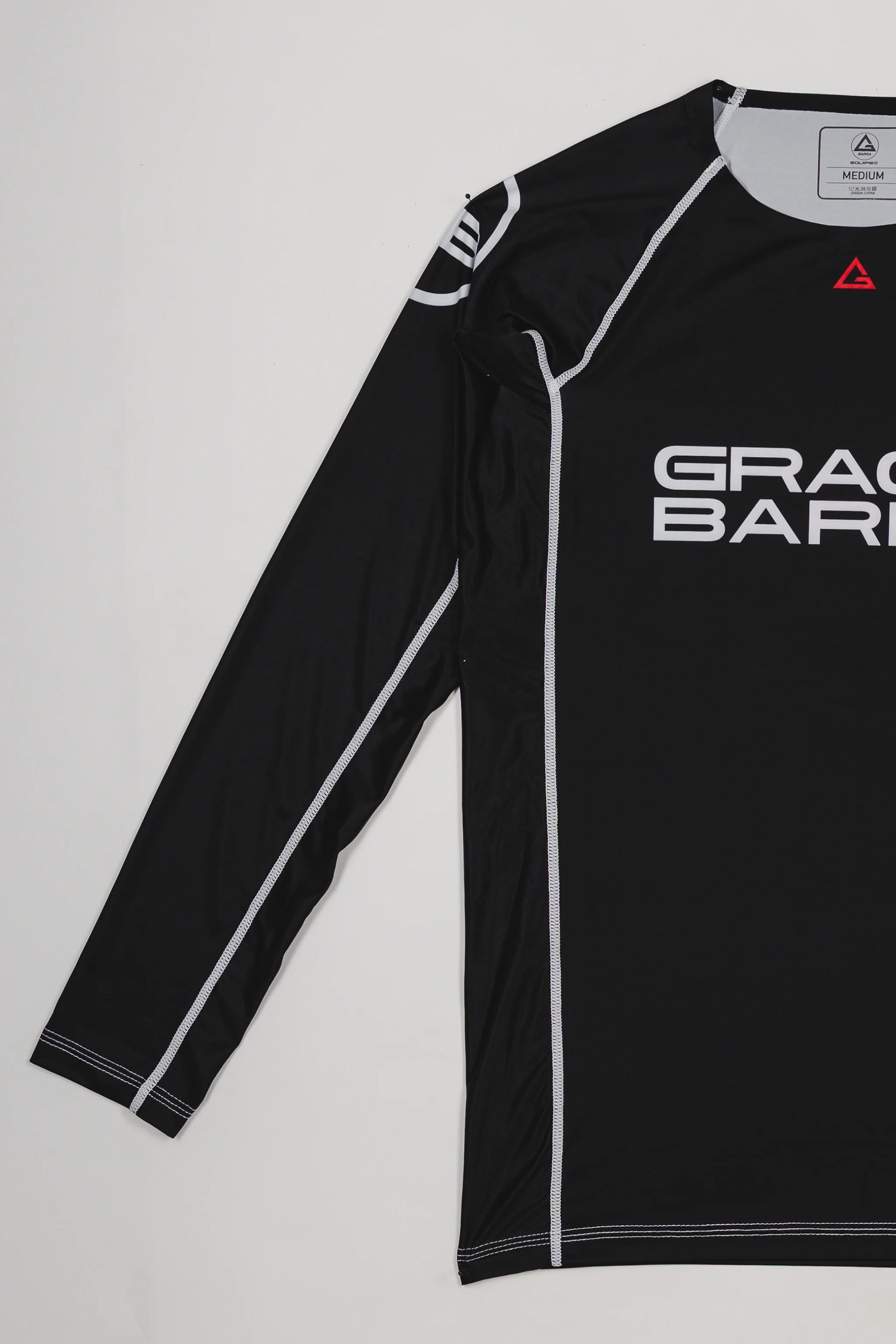 Side view of the black Lutador Longsleeve Ranked Rashguard showing the full black sleeve with white contrast stitching and the Gracie Barra chest logo.
