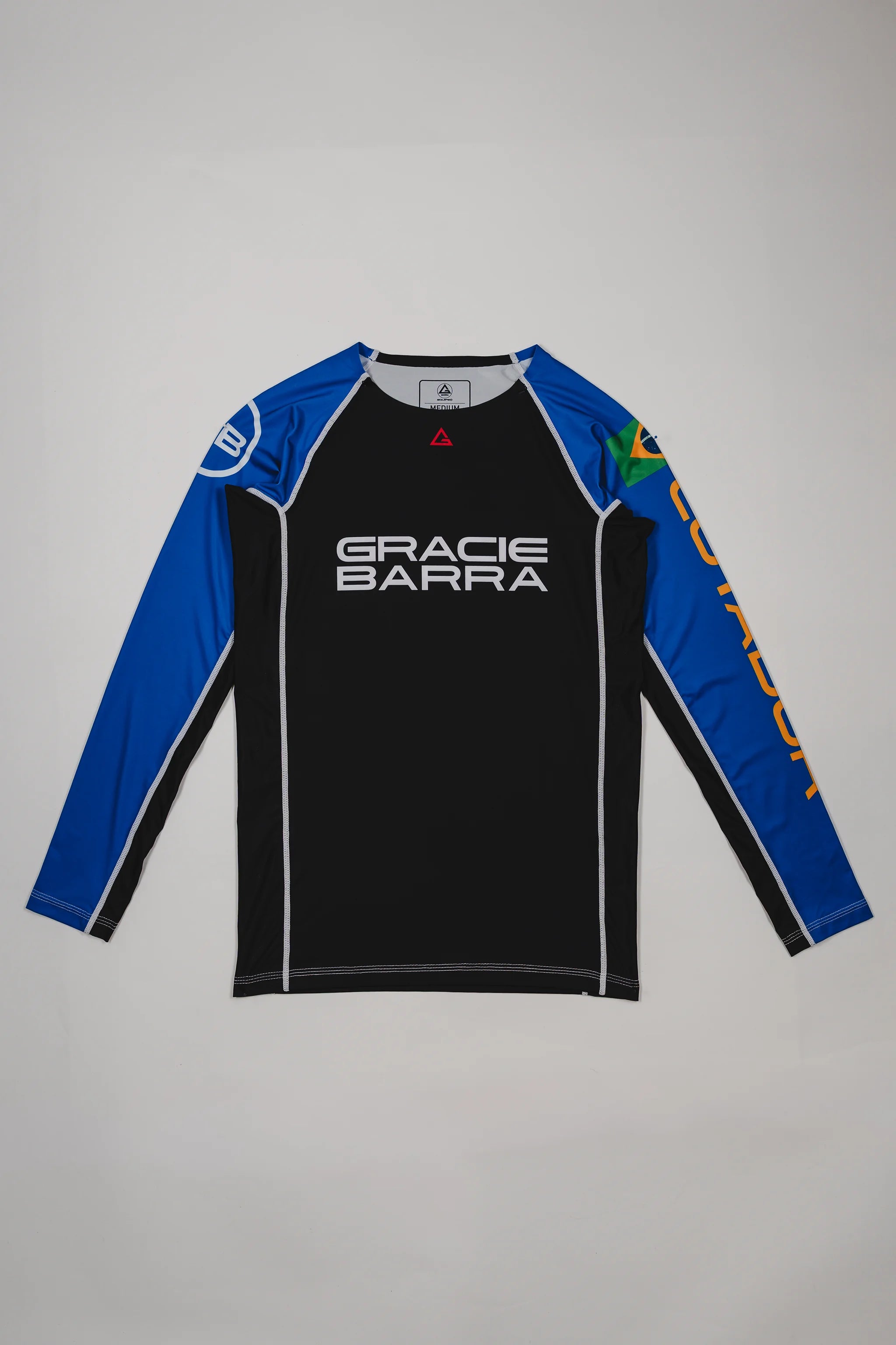 Full front view of the Lutador Longsleeve Ranked Rashguard in blue, featuring black torso, blue raglan sleeves, Gracie Barra wordmark, Brazilian flag arm patch, and gold ‘Lutador’ sleeve print.