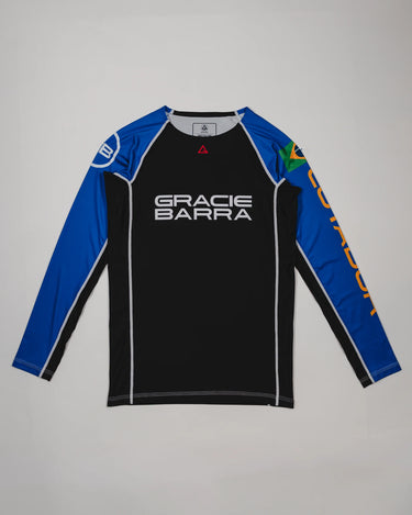 Full front view of the Lutador Longsleeve Ranked Rashguard in blue, featuring black torso, blue raglan sleeves, Gracie Barra wordmark, Brazilian flag arm patch, and gold ‘Lutador’ sleeve print.