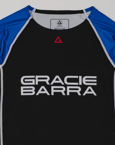 Close-up of the Lutador Longsleeve Ranked Rashguard in blue, showing the black torso, blue raglan sleeves, red Legacy G chest logo, and large white Gracie Barra wordmark.