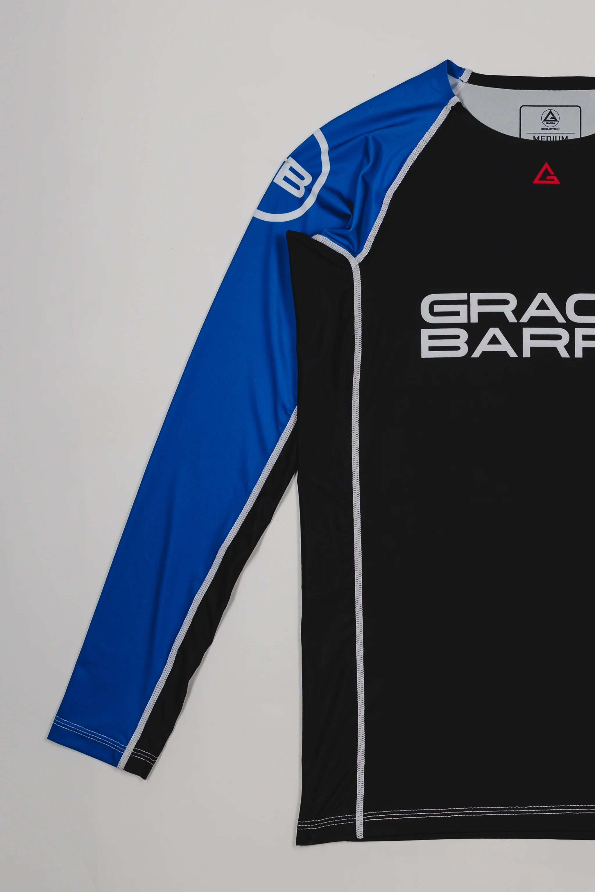 Side view of the Lutador Longsleeve Ranked Rashguard in blue, showing the full blue raglan sleeve with the white GB circle logo and the black torso with Gracie Barra branding.