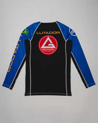 Back view of the Lutador Longsleeve Ranked Rashguard in blue, showing the large red Barra Shield, gold ‘Lutador’ text, Brazilian flag sleeve patch, and contrasting black torso panel.