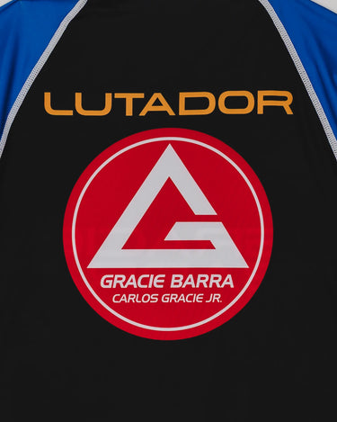 Close-up of the back of the Lutador Longsleeve Ranked Rashguard in blue, showing the gold ‘Lutador’ text above the large red Barra Shield on the black panel.