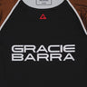 Close-up of the Lutador Longsleeve Ranked Rashguard in brown, showing the black torso, brown raglan sleeves, red Legacy G chest logo, and large white Gracie Barra wordmark.