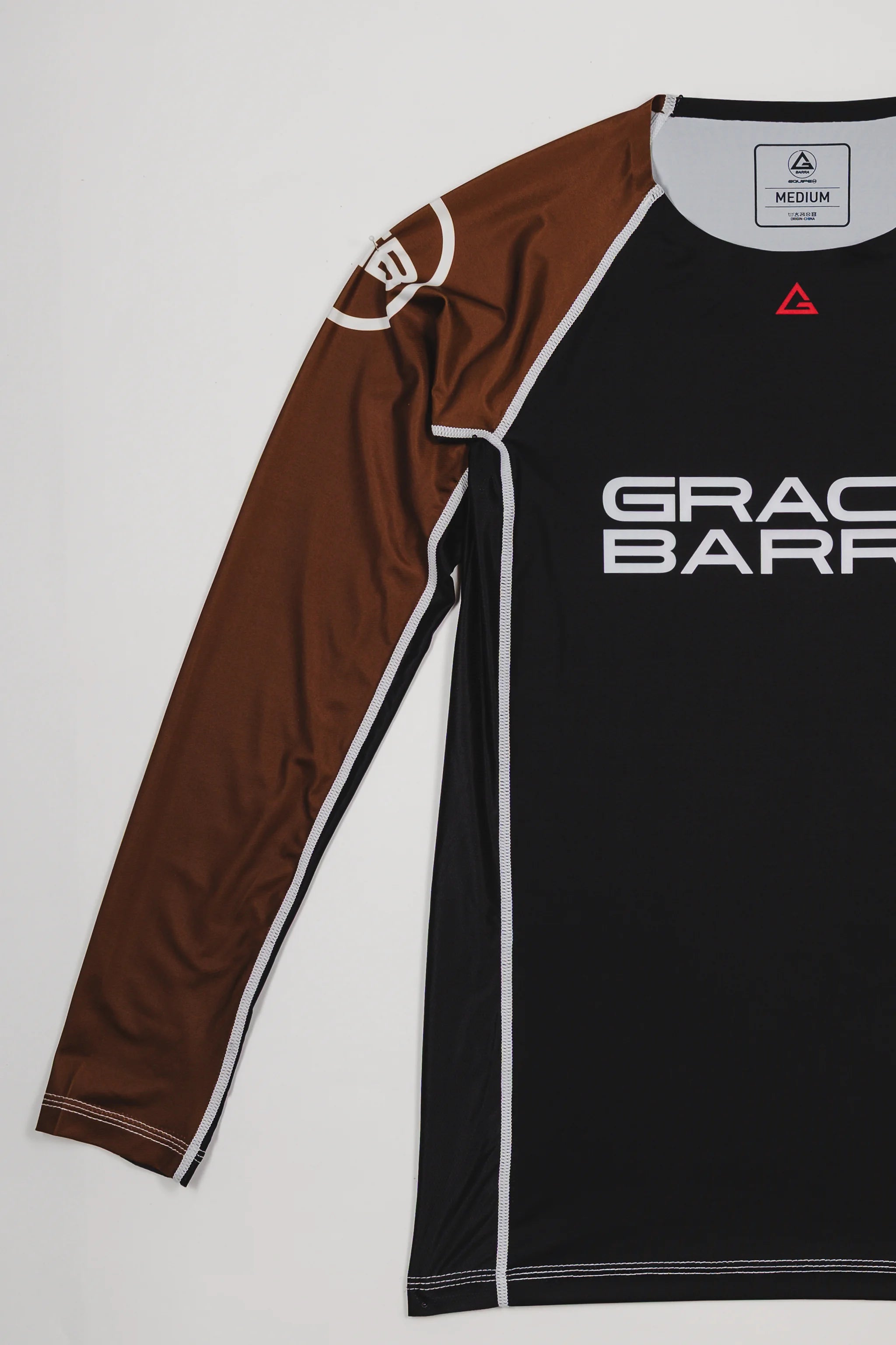 Side view of the Lutador Longsleeve Ranked Rashguard in brown, showing the full brown raglan sleeve with the white GB circle logo and the black torso with Gracie Barra branding.
