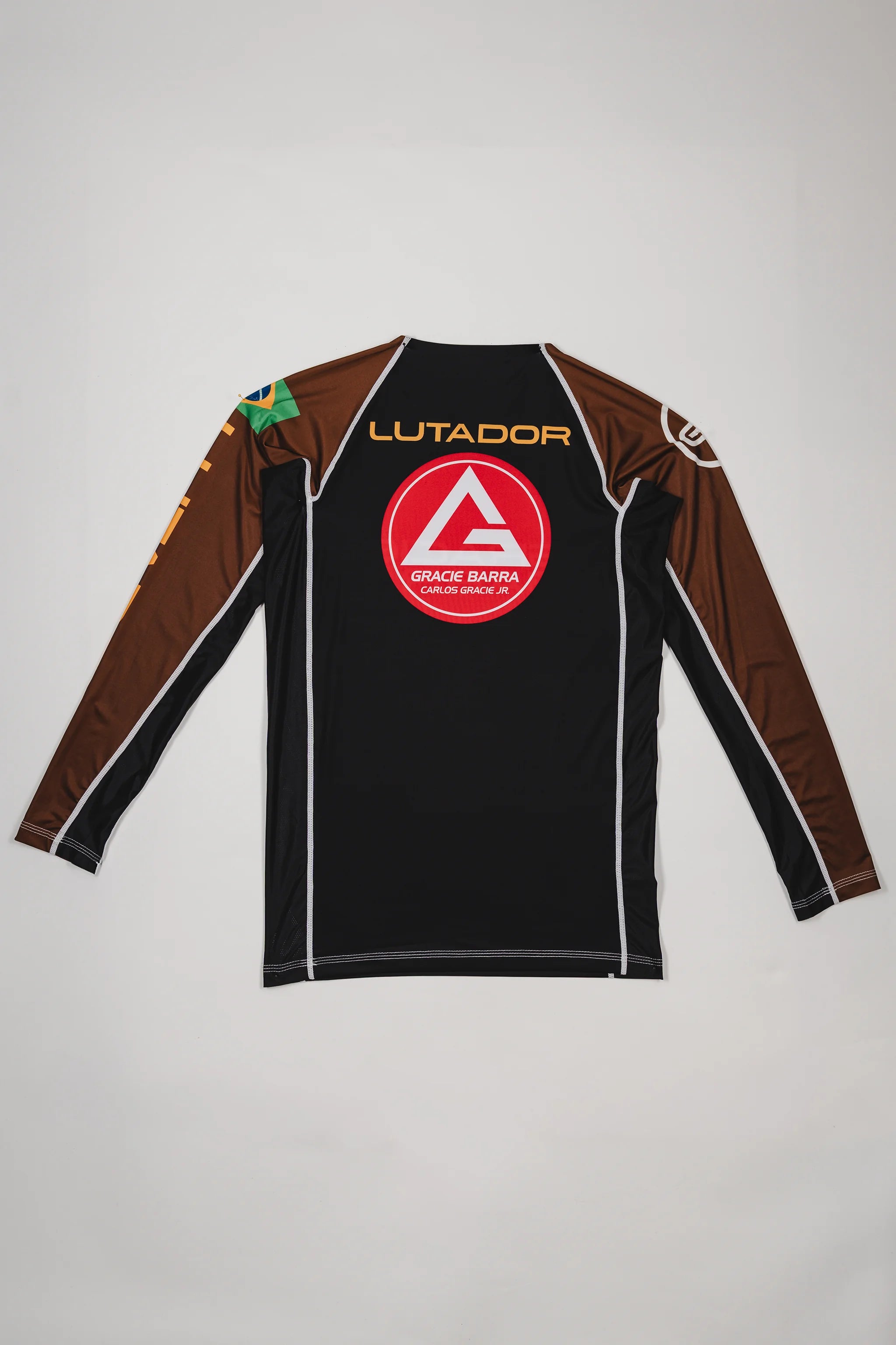 Back view of the Lutador Longsleeve Ranked Rashguard in brown, showing the large red Barra Shield, gold ‘Lutador’ text, Brazilian flag sleeve patch, and brown raglan sleeves.