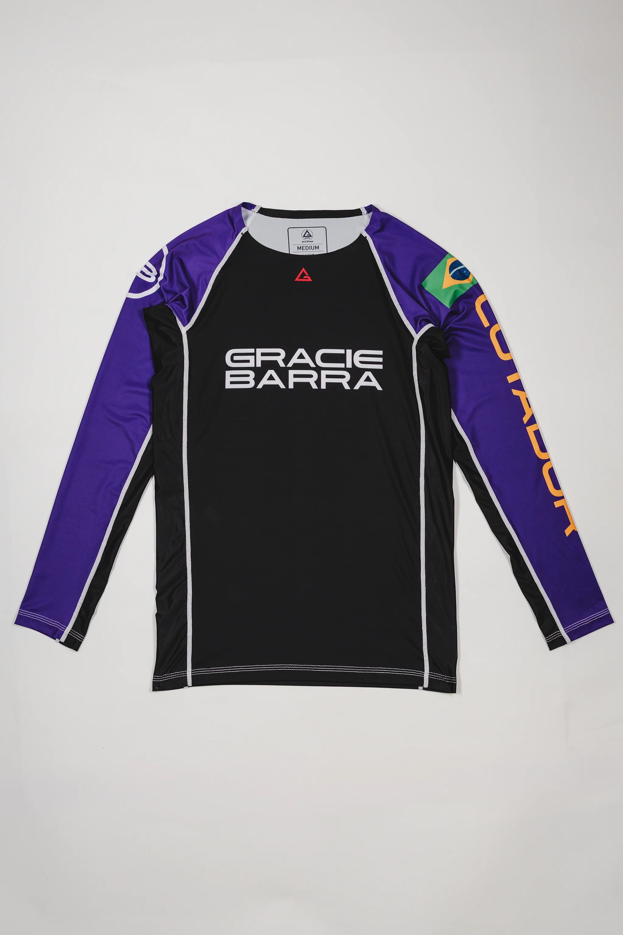 Full front view of the Lutador Longsleeve Ranked Rashguard in purple, featuring black torso, purple raglan sleeves, Gracie Barra wordmark, Brazilian flag arm patch, and gold ‘Lutador’ sleeve print.