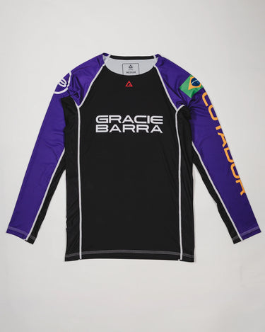 Full front view of the Lutador Longsleeve Ranked Rashguard in purple, featuring black torso, purple raglan sleeves, Gracie Barra wordmark, Brazilian flag arm patch, and gold ‘Lutador’ sleeve print.