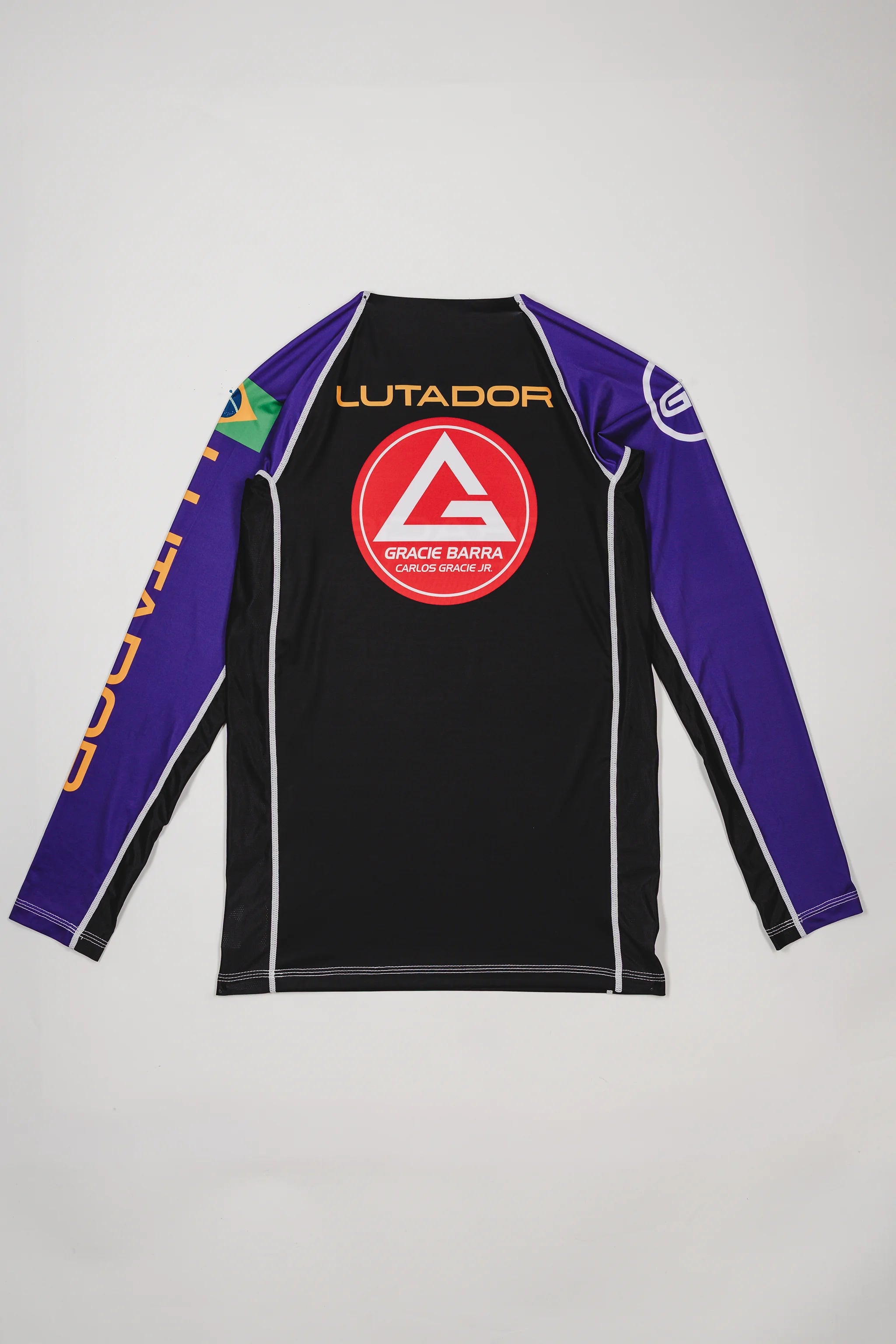 Back view of the Lutador Longsleeve Ranked Rashguard in purple, showing the large red Barra Shield, gold ‘Lutador’ text, Brazilian flag sleeve patch, and purple raglan sleeves.