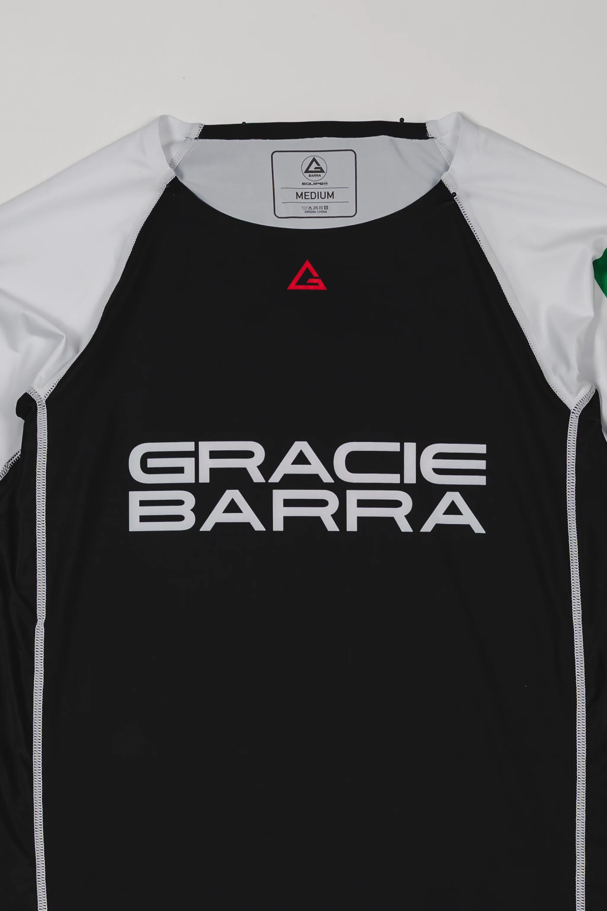 Front view of the Lutador Longsleeve Ranked Rashguard showing the black torso, white raglan sleeves, red Legacy G chest logo, and large white Gracie Barra wordmark.