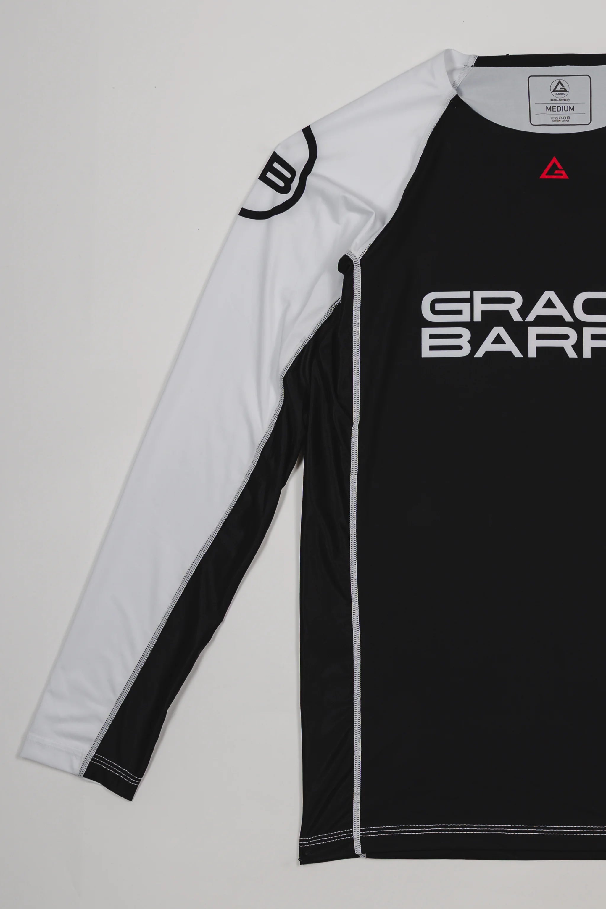 Side view of the Lutador Longsleeve Ranked Rashguard showing the full white raglan sleeve with the black GB circle logo and the black torso with Gracie Barra branding.