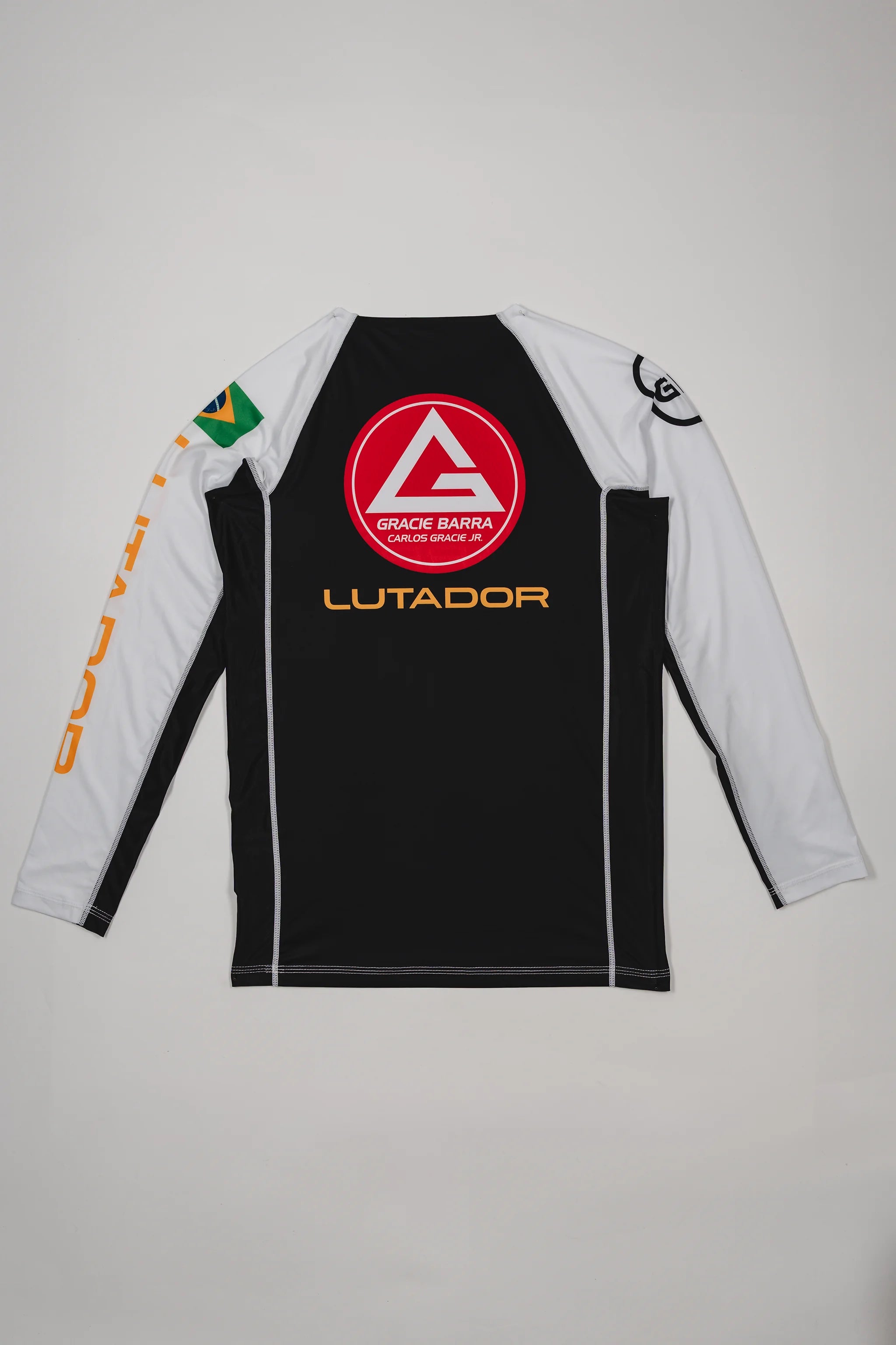 Back view of the Lutador Longsleeve Ranked Rashguard showing the large red Barra Shield, gold ‘Lutador’ text, Brazilian flag arm patch, and black-and-white paneling.