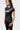 Side angle of the black Gracie Barra Proximity Womens Training Tee showing the gray diagonal panel wrapping the side seam and the standard fit.