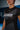 Close-up of the white Gracie Barra chest wordmark, Legacy G triangle, and gray diagonal mesh panels on the black Proximity womens training tee.