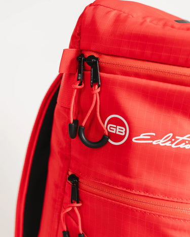 Close-up of Red Comp GB4 Backpack showing GB Edition logo, black pull tabs, and detailed red zippers on the side pocket panel.