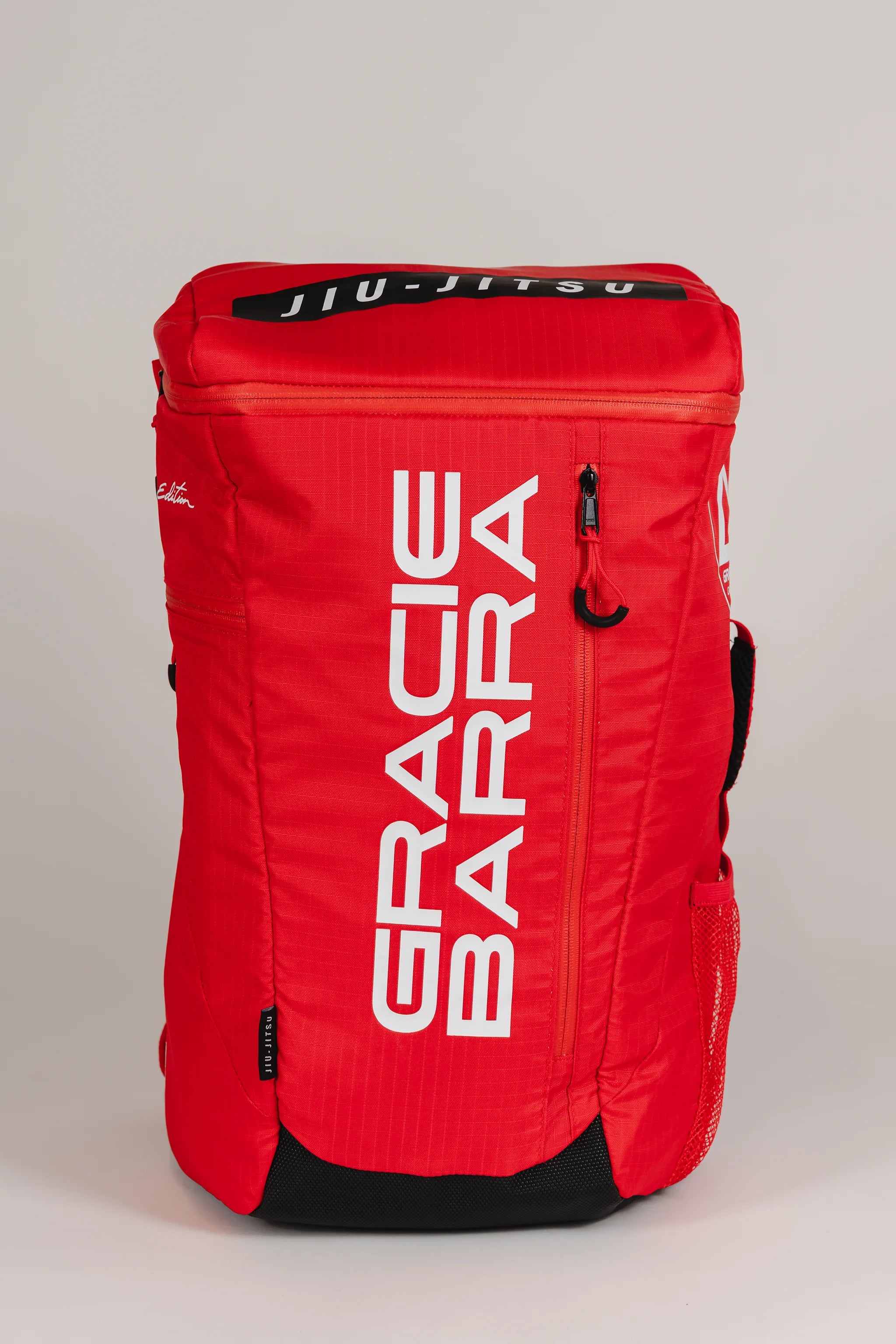 Front view of Red Comp GB4 Backpack featuring bold vertical “Gracie Barra” logo and black “Jiu-Jitsu” patch on top, part of the official Red Comp Collection.