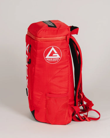 Side profile of Red GB4 Kids Backpack from the Gracie Barra Red Comp Collection, showing round GB logo patch, mesh side pocket, and structured athletic design.