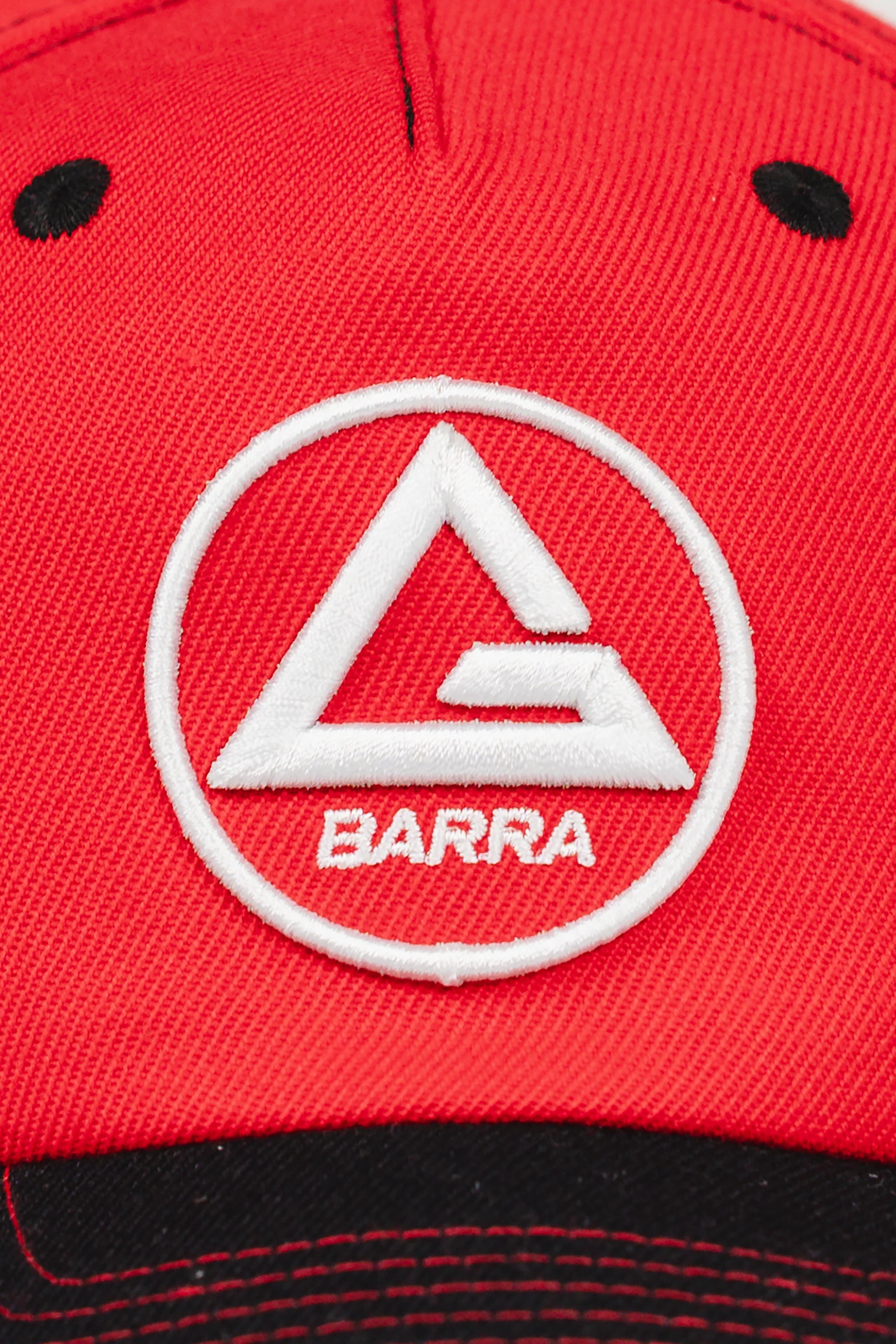 Close-up of the Red Comp Team Cap showing raised white embroidery of the Red Shield logo on GB Red twill fabric above a black brim.