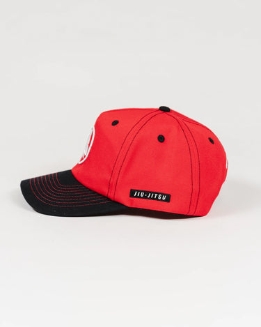 Side view of the Red Comp Team Cap showing the black brim, GB Red crown, and woven JIU-JITSU label above the side seam.