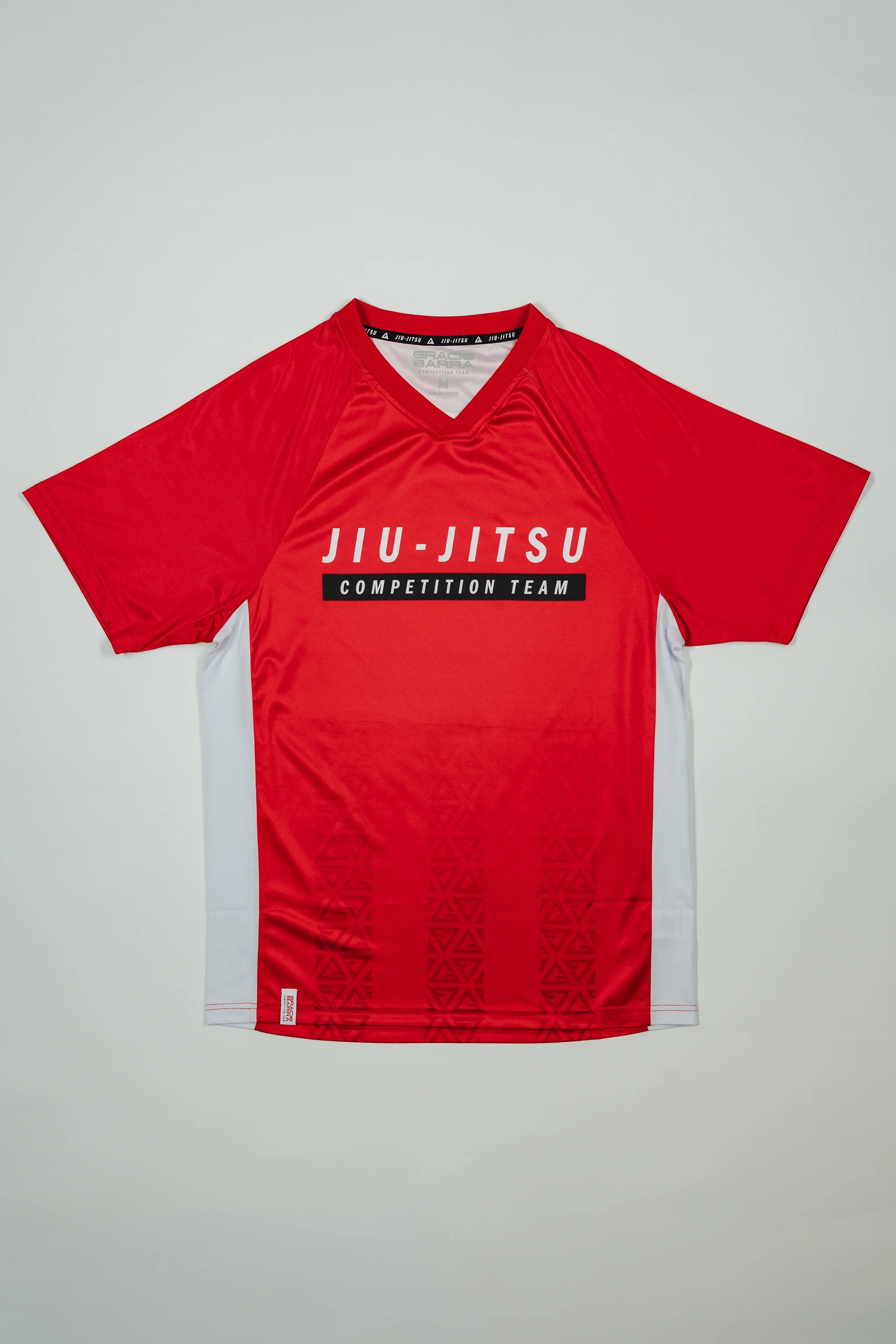 Flat-lay of the Men’s Red Comp Team Jersey featuring the official Jiu-Jitsu Competition Team graphic and tonal Legacy G pattern on a light background.