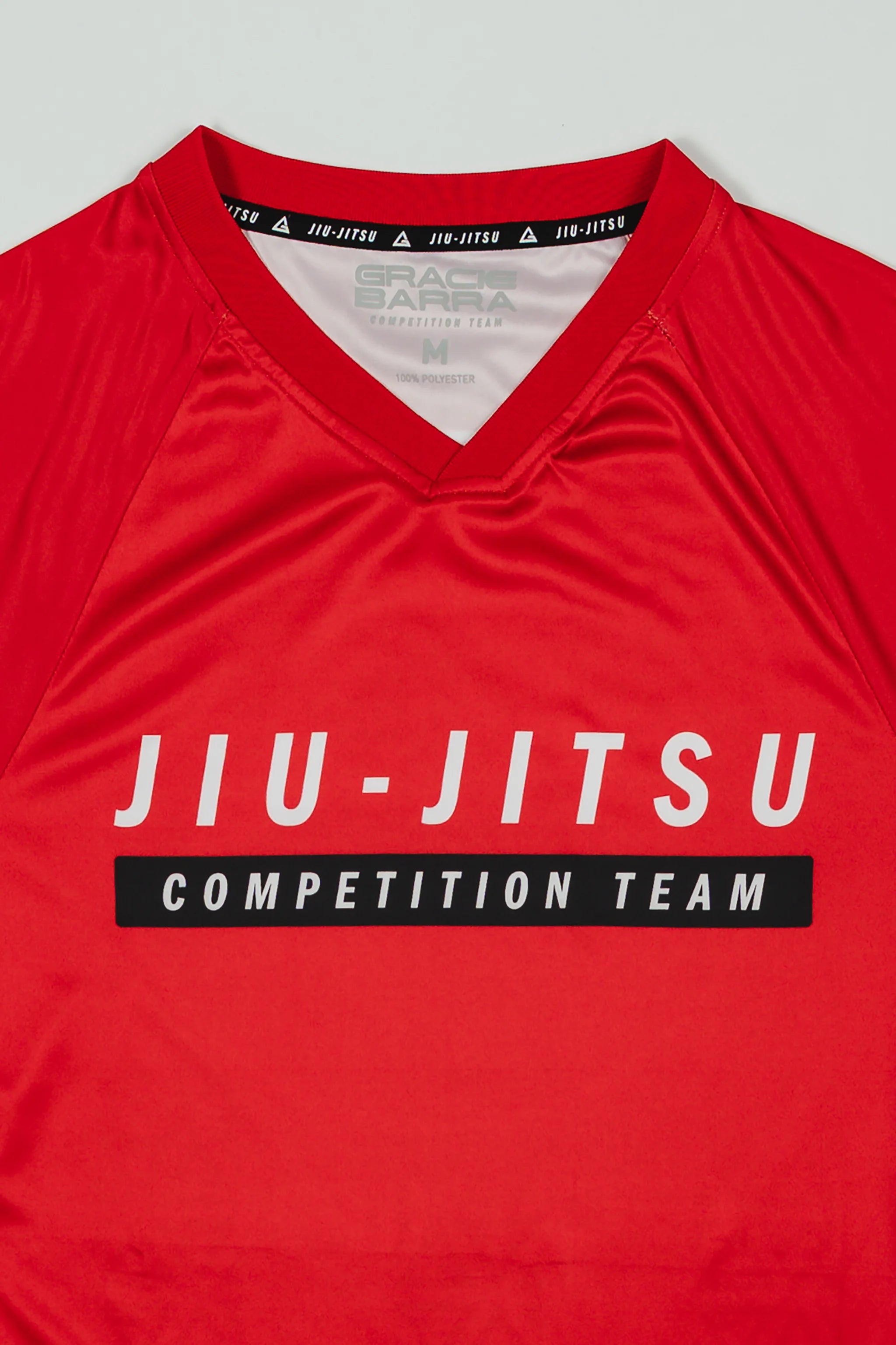 Close-up of the Men’s Red Comp Team Jersey showing the official Jiu-Jitsu Competition Team front graphic and ribbed V-neck collar with interior GB trim.