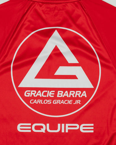 Close-up of the Men’s Red Comp Team Jersey back showing the Gracie Barra red shield logo with “Carlos Gracie Jr.” and “Equipe” text printed in white.