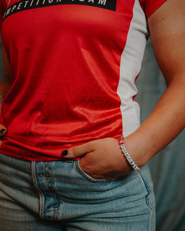 Close-up of a Professor Keanna wearing the Red Comp Women’s Team Jersey showing the official Jiu-Jitsu Competition Team graphic and tonal Legacy G pattern.
