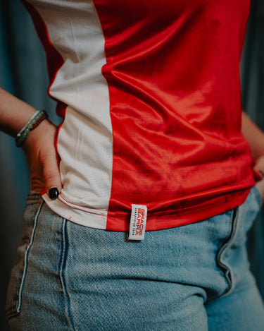 Side profile close-up of a Professor Keanna wearing the Red Comp Women’s Team Jersey, showing the woven Gracie Barra label and white side mesh panel.