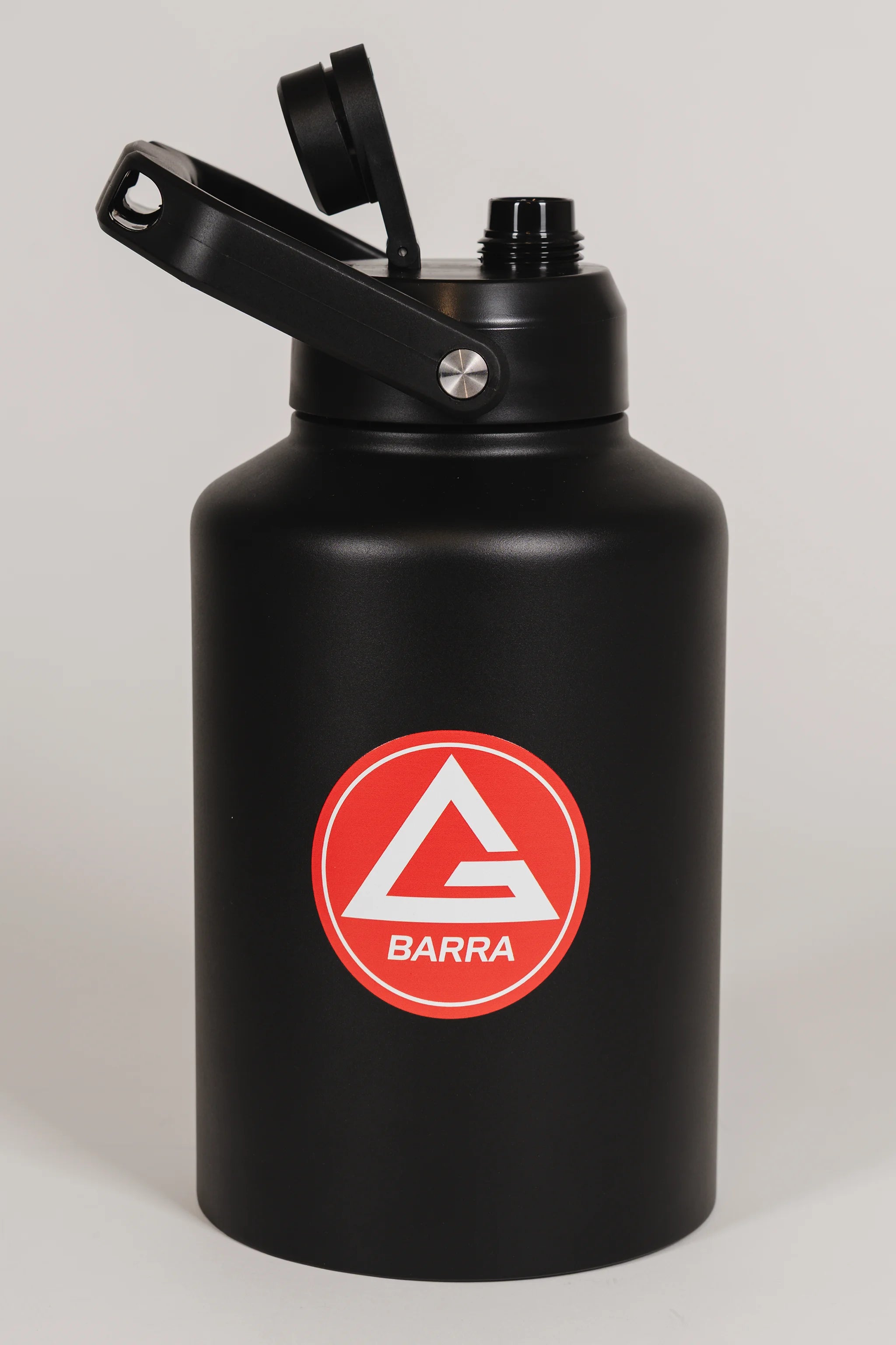 Black stainless steel 128 oz Red Shield bottle with the Gracie Barra Red Shield logo on the front, shown with the lid open, photographed against a light background.