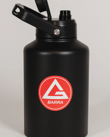 Black stainless steel 128 oz Red Shield bottle with the Gracie Barra Red Shield logo on the front, shown with the lid open, photographed against a light background.