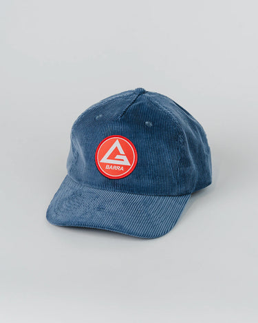 Blue corduroy 5-panel Red Shield Elite Cap with a curved visor and woven Barra Shield patch on the front panel, photographed flat against a white background.