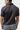 Back of the black Red Shield Terra Mar polo on a student, showing the plain back panel, yoke seam and folded collar.