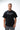 Rio Roots Mens Tee in Black — front view on model showing the Gracie Barra Estd 1986 chest graphic and relaxed oversized fit.