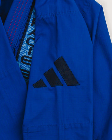 Sleeve detail of blue Ripstop Lite Men’s BJJ kimono by adidas and Gracie Barra, showing black adidas logo and front chest patch with Legacy G pattern in blue.