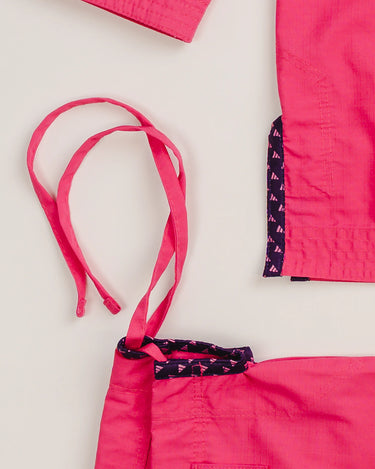 Close-up of pink Ripstop Lite Women’s BJJ kimono by adidas and Gracie Barra, showing drawstring gi pants and interior seam tape with repeating adidas logo pattern.
