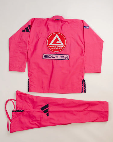 Back view of pink Ripstop Lite Women’s BJJ kimono by adidas and Gracie Barra, featuring large Red Shield patch, “Equipe” embroidery, and matching drawstring pants with black adidas logo.