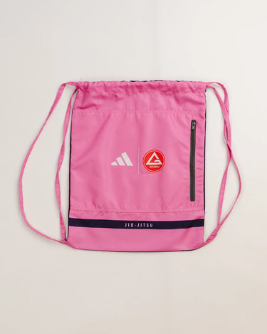 Pink drawstring kimono bag by adidas and Gracie Barra, featuring Red Shield patch, white adidas logo, black zipper pocket, and “Jiu-Jitsu” text detail.