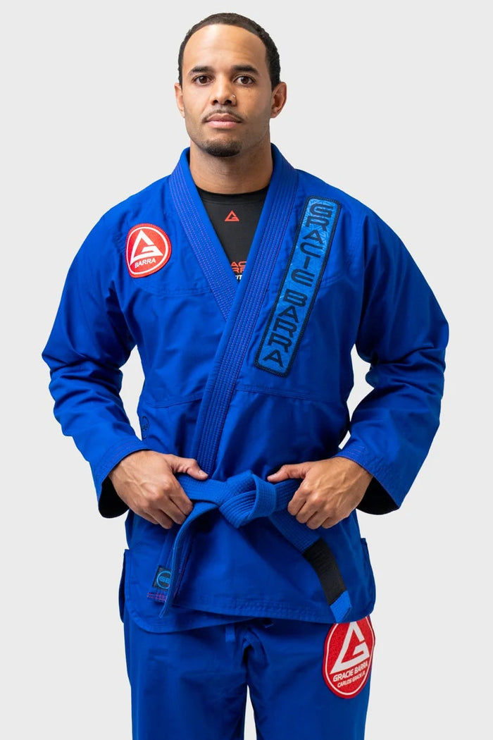 Student wearing the blue Gracie Barra Ripstop Lightweight Kimono with the red Barra Shield on the shoulder and the Gracie Barra lapel patch, front view.