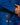 Close-up of a man wearing the blue Ripstop Lightweight Kimono jacket with a black belt, hands clasped at the waist, showing the round Gracie Barra chest patch and red contrast stitching