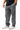 Ripstop Utility Pants in Gray — angled back view on model with hand in pocket, showing the tonal Gracie Barra embroidery and red-stitched pocket.