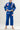 Kids model wearing Sakura V3 blue BJJ Gi with pink Red Shield logo, Gracie Barra lapel detail, and Sakura embroidery, standing on white background.