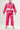 Kids model wearing Sakura V3 pink BJJ Gi with Red Shield chest logo, Gracie Barra lapel detail, and Sakura embroidery, standing on white background.