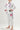 Front three-quarter view of kids model wearing Sakura V3 white BJJ Gi with pink stitching, vertical Gracie Barra lapel detail, Red Shield logos, and purple Sakura embroidery on pants.