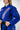 Close-up of Sakura V3 Women’s Kimono in blue showing vertical Gracie Barra chest branding, Red Shield logo, sleeve detail, and pearl weave texture