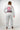 Rear view of female athlete wearing the Sakura V3 Women’s Kimono in white featuring large Red Shield back logo, Equipe detail, and purple Sakura embroidery on white background
