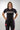 Female model wearing Sakura V3 Women’s black BJJ rashguard with purple stitching and Gracie Barra logo, front view, studio background