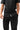 Stacked Button Up in Black — waist close-up showing the front button placket, curved hem, and white woven hem tag over black pants.